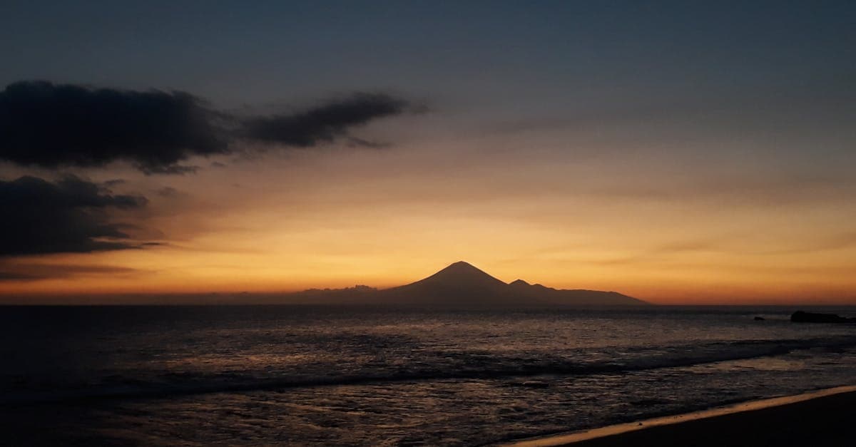 Matahari terbenam di Pantai Batu Layar dengan siluet gunung, inspirasi memilih waktu terbaik berkunjung ke Jepang