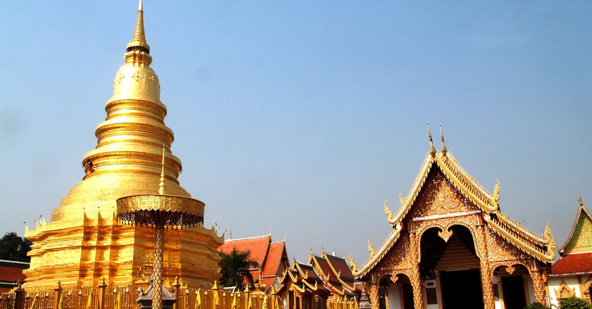 Gleaming golden Buddhist temple with traditional tiered rooflines against a vivid blue sky in Thailand