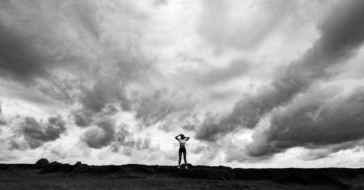 Dramatyczna sylwetka człowieka na tle burzowych chmur, symbol monsunowej pory roku w Tajlandii.