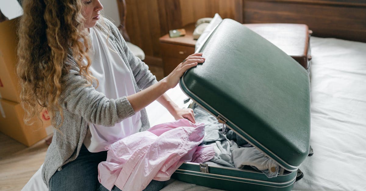 Woman packing a suitcase in a bedroom, planning for Ireland's unpredictable weather conditions