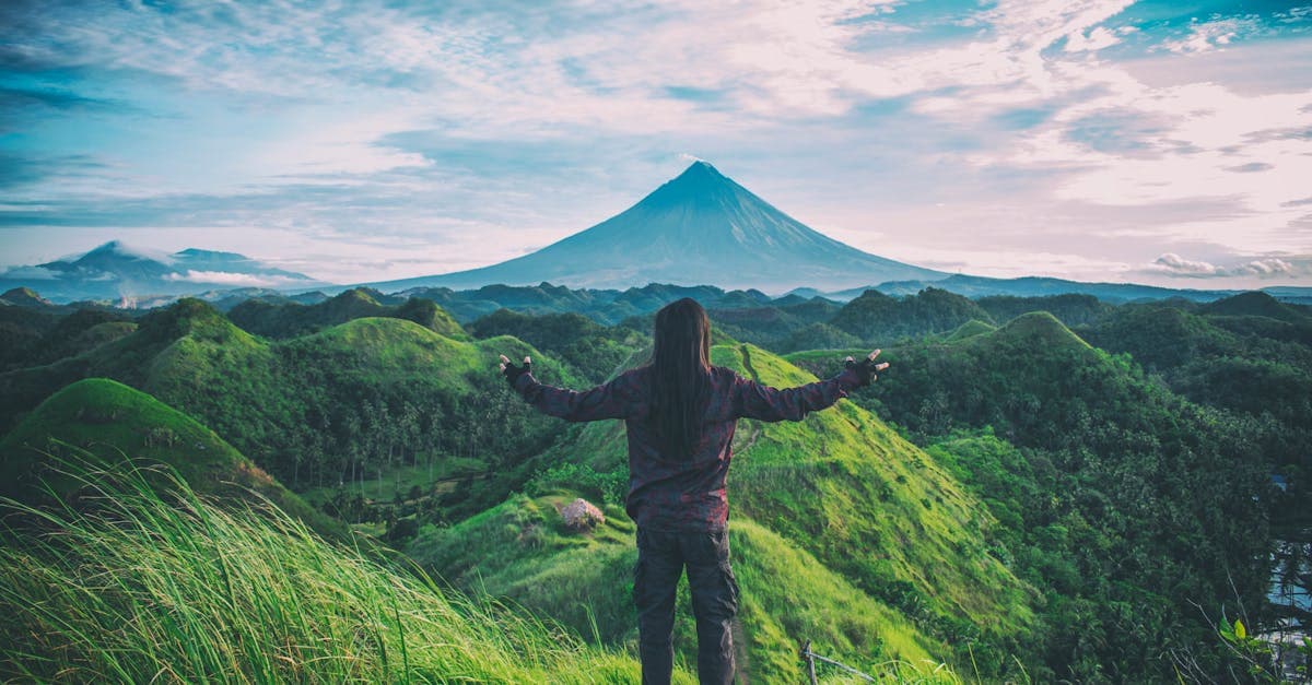 Viajero contemplando el volcán Mayon rodeado de colinas verdes en Bicol, Filipinas, uno de los mejores destinos para viajar solo.