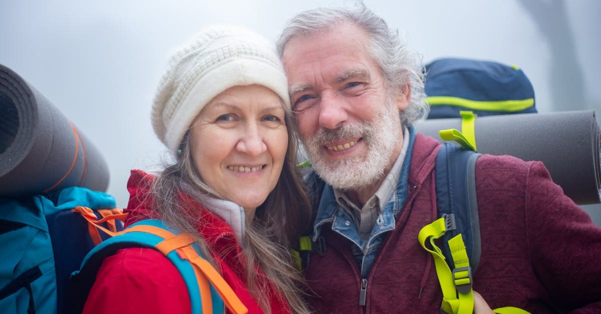 Senior couple hiking with backpacks through misty mountain trails, highlighting coverage needs for older Singapore travellers.