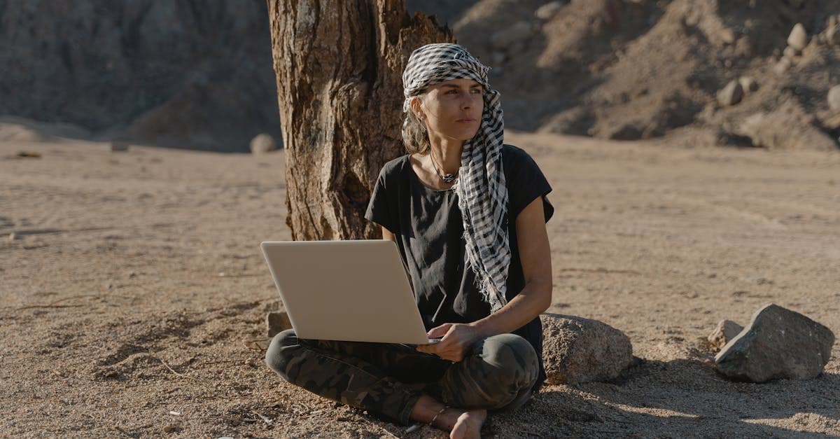Woman working barefoot on a laptop under a tree in an arid landscape, among the best countries for digital travel eSIMs.