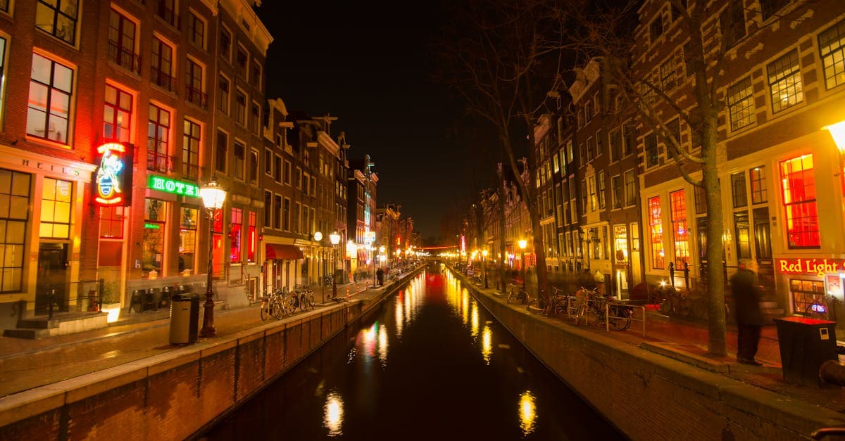 Amsterdam canal at night with glowing reflections on water in the vibrant Jordaan neighbourhood