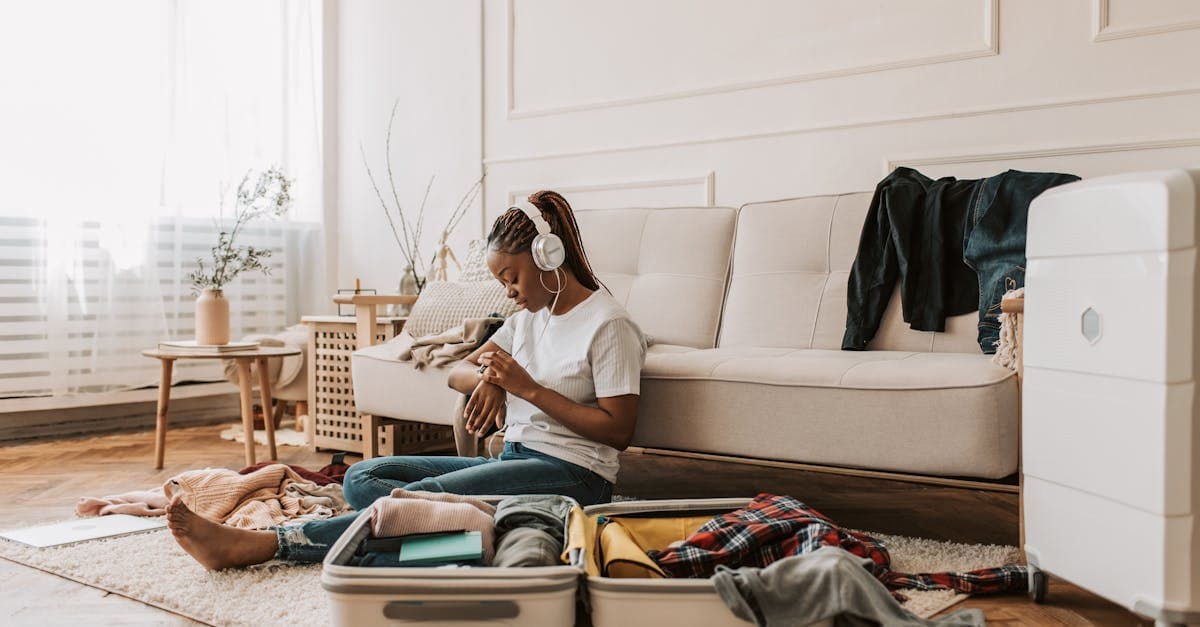 Young woman reviewing her Ireland packing list while folding clothes beside an open suitcase