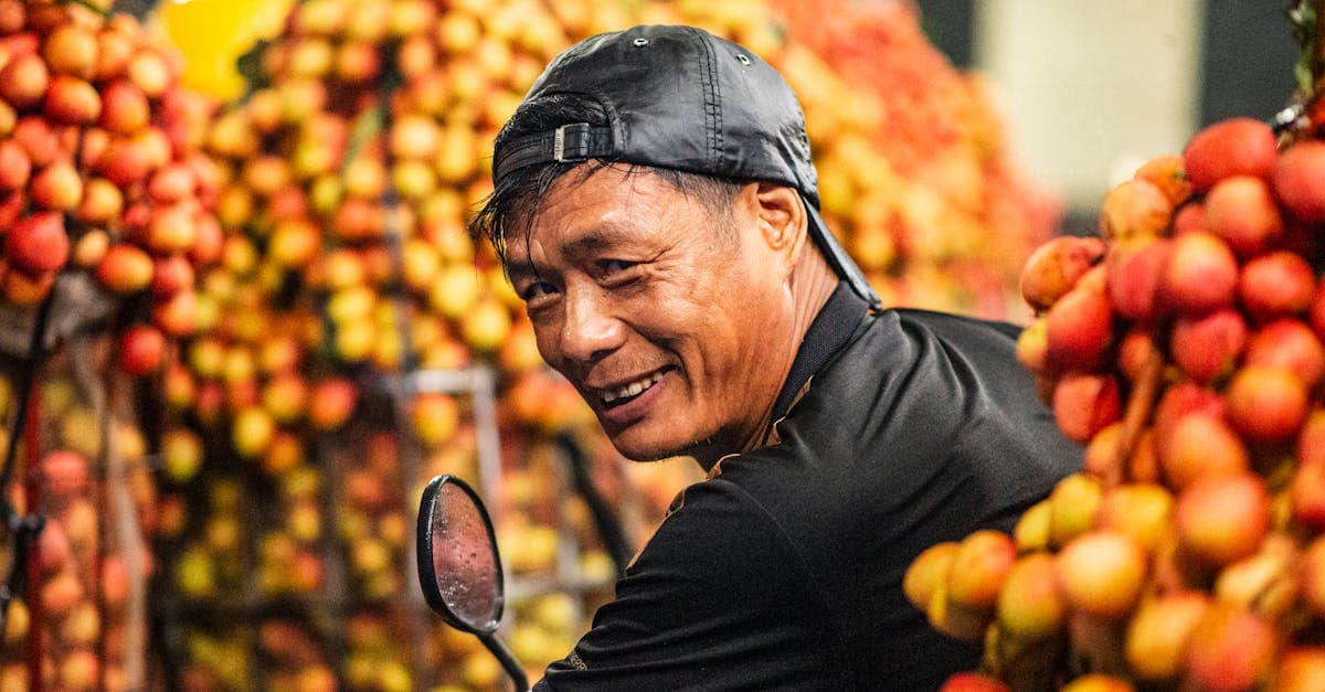 Vendeur joyeux entouré de litchis à Bac Giang, nourriture vietnam accessible pour tout budget de voyage